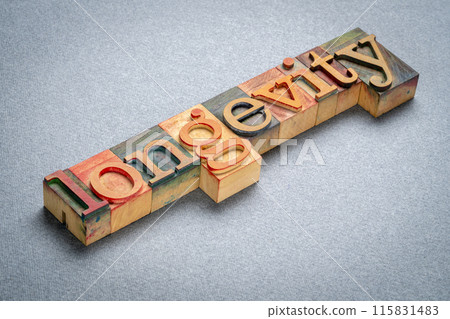 longevity text in retro letterpress wood type stained by color inks, lifespan and aging concept 115831483