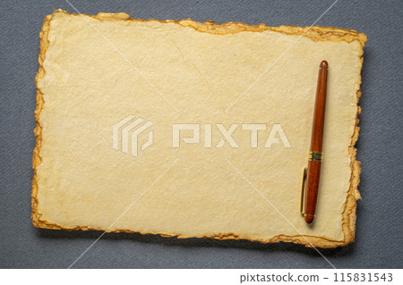 stack of tan toned heavyweight deckle edge paper sheets with a stylish pen 115831543