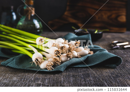 Stems of fresh sweet garleek on a cloth on the table Stems of fresh sweet garleek on a cloth on the table 115831644