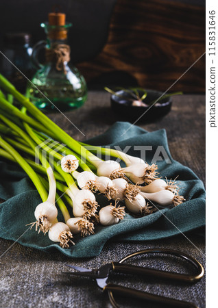 Stems of fresh sweet garleek on a cloth on the table vertical view Stems of fresh sweet garleek on a cloth on the table vertical view 115831646