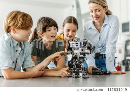 Children learning robotics in Elementary school. Young students building robot in after school robotics club. Field trip to real robotics laboratory. 115831949