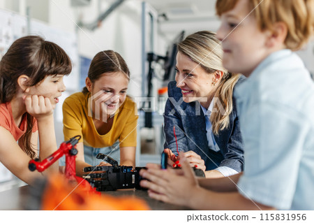 Children learning robotics in Elementary school. Young students building robot in after school robotics club. Field trip to real robotics laboratory. Children learning robotics in Elementary school. Young students building robot in after school robotics club. Field trip to real robotics laboratory. 115831956