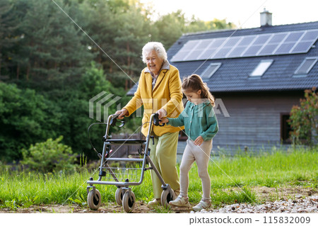 Granddaughter spending time with elderly grandma, companionship. Senior lady with walker spending time in nature. 115832009