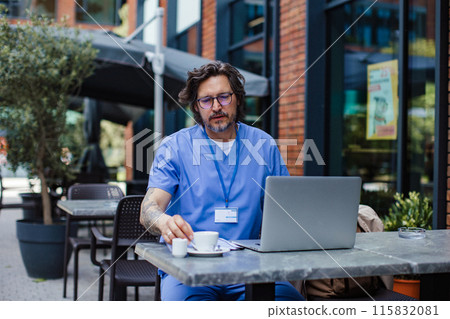 Doctor enjoying cup of coffee in coffee shop, working on laptop. Telemedicine consultation online. Mental health and life balance for a healthcare worker. 115832081
