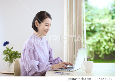 中年婦女在客廳喝咖啡時看著電腦 115834279