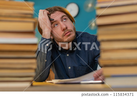 Exhausted businessman moving stacks of books and reviewing documents reports working hard in office 115834371