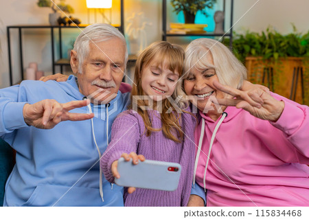 Child girl granddaughter with grandparents make blogger selfie smartphone portrait shows peace sign 115834468
