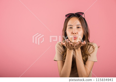 Asian happy portrait beautiful cute young woman teen standing blowing kiss air something on palm hands expresses her love looking to camera studio shot isolated on pink background with copy space Asian happy portrait beautiful cute young woman teen standing blowing kiss air something on palm hands expresses her love looking to camera studio shot isolated on pink background with copy space 115834941