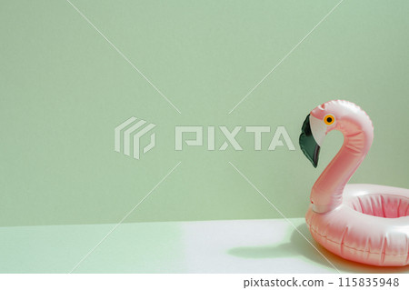 Summer vacation concept. Pink flamingo bird shape swimming pool tube on mint green background Summer vacation concept. Pink flamingo bird shape swimming pool tube on mint green background 115835948