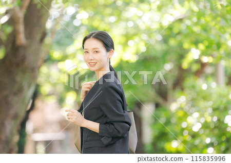 一個穿著西裝的女人在新綠色中轉身 115835996