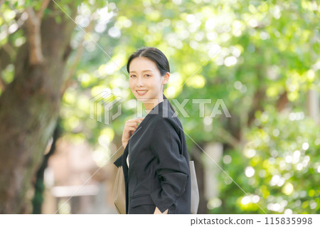 一個穿著西裝的女人在新綠色中轉身 115835998