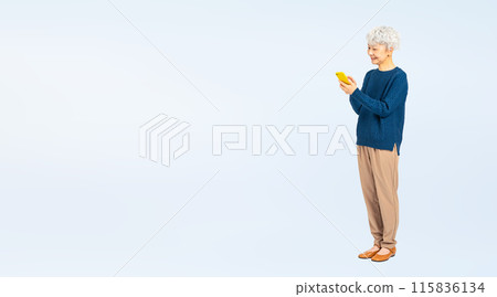 Full-body photo of a smiling senior woman using a smartphone 115836134
