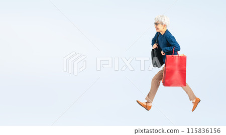 Full body photo of a senior woman jumping with shopping bags 115836156