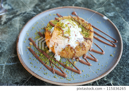 Gourmet dessert with pistachio garnish and chocolate drizzle beautifully presented on a plate 115836265