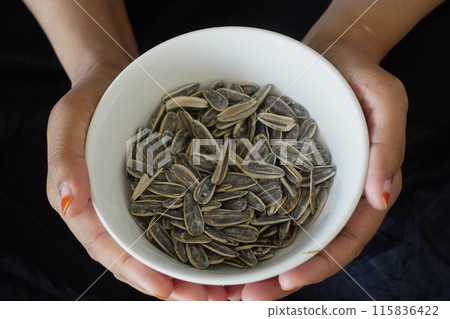 woman holding a bowl of sun flower seeds woman holding a bowl of sun flower seeds 115836422