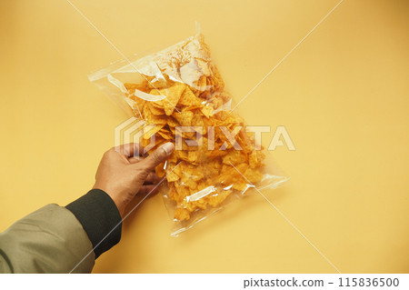 holding a open chips packet top view  holding a open chips packet top view  115836500