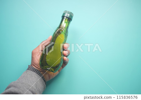 hand holding a bottle of olive oil hand holding a bottle of olive oil 115836576