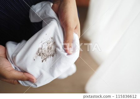 women holding white color dirty shirt, showing making stain 115836612