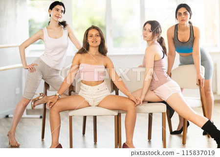 Young female dancers in stiletto heels posing on chairs in studio Young female dancers in stiletto heels posing on chairs in studio 115837019