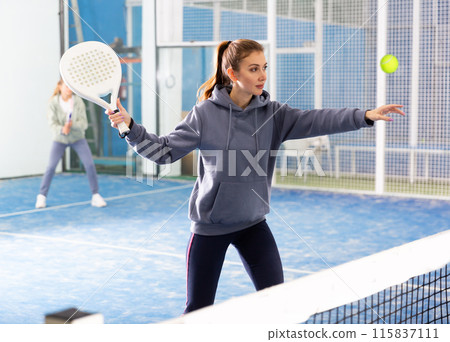 Woman and man learning to play padel on tennis court 115837111