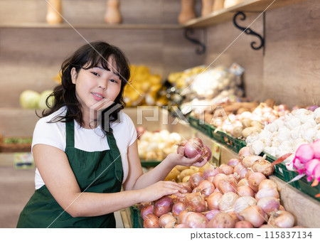 Young asian salesgirl arranging onions on display at market Young asian salesgirl arranging onions on display at market 115837134