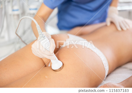 Cosmetologist performing high-frequency ultrasound procedure on female buttocks 115837183