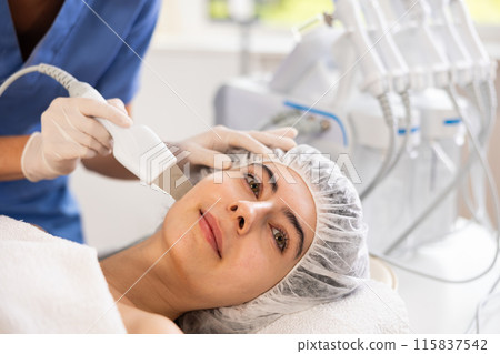 Young woman cosmetologist doing exfoliation procedure to young woman Young woman cosmetologist doing exfoliation procedure to young woman 115837542