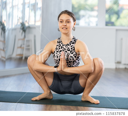 Skilled girl demonstrating frog pose of yoga in training room Skilled girl demonstrating frog pose of yoga in training room 115837878