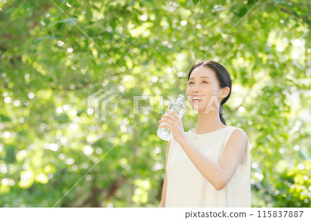 A woman drinking water of a plastic bottle 115837887