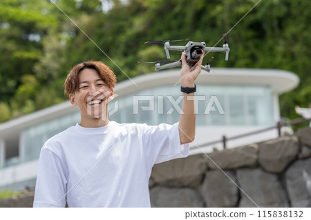 Japanese man enjoying drone photography outdoors on a sunny day | Drone image Japanese man enjoying drone photography outdoors on a sunny day | Drone image 115838132