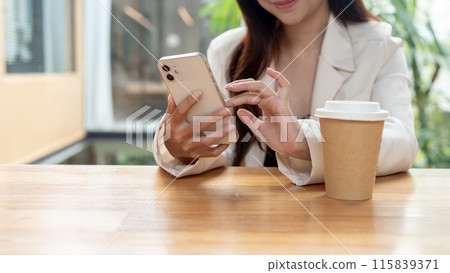 A cropped image of a beautiful Asian businesswoman sitting in a coffee shop, using her smartphone. 115839371