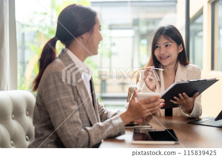 A charming Asian businesswoman is having a meeting with her colleague in the meeting room. A charming Asian businesswoman is having a meeting with her colleague in the meeting room. 115839425