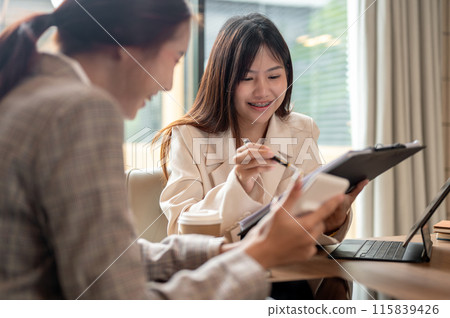 A charming Asian businesswoman is having a meeting with her colleague in the meeting room. 115839426