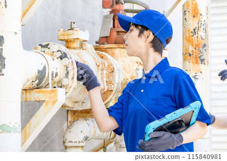 Worker inspecting pipes using a tablet Worker inspecting pipes using a tablet 115840981