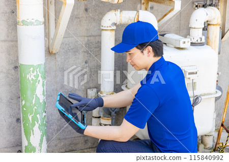 Worker inspecting pipes using a tablet 115840992