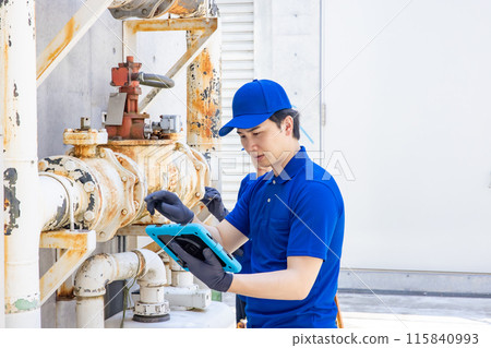 Worker inspecting pipes using a tablet 115840993