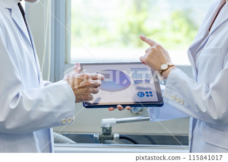 A group of researchers and doctors looking at a tablet A group of researchers and doctors looking at a tablet 115841017