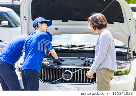 Worker inspecting the engine compartment of a car Worker inspecting the engine compartment of a car 115841028