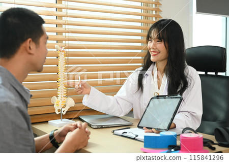 Female physical therapist holding a digital tablet giving consultation male patient at rehabilitation clinic Female physical therapist holding a digital tablet giving consultation male patient at rehabilitation clinic 115841296