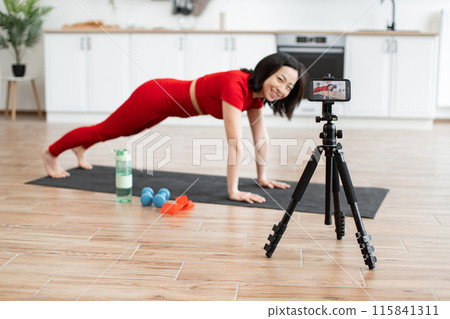 Woman practicing yoga at home with online video tutorial 115841311