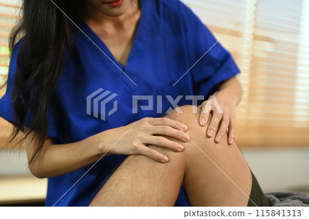 Cropped shot of physiotherapist treating injured knee of athlete man patient. Sport physical therapy and rehabilitation Cropped shot of physiotherapist treating injured knee of athlete man patient. Sport physical therapy and rehabilitation 115841313