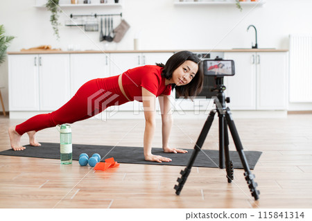 Woman in red activewear practicing yoga at home on video call 115841314