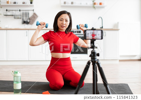 Woman exercising with dumbbells during home workout session 115841323