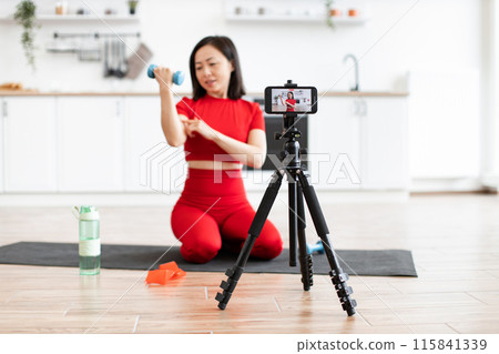 Young woman recording fitness video with smartphone at home 115841339