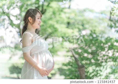 An Asian pregnant woman taking maternity photos in the sunlight filtering through the fresh greenery An Asian pregnant woman taking maternity photos in the sunlight filtering through the fresh greenery 115841437