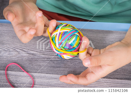 Preschooler hands with ball of rubber bands or erasers 115842106