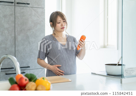 A pregnant woman cooking with a tired expression in the kitchen (dissatisfaction, stress, fatigue) A pregnant woman cooking with a tired expression in the kitchen (dissatisfaction, stress, fatigue) 115842451