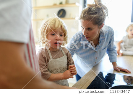 Young boy burn his finger while helping in kitchen. Mother soothing him. Young boy burn his finger while helping in kitchen. Mother soothing him. 115843447