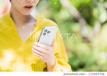 一位女士在戶外操作智慧型手機。 一位女士在戶外操作智慧型手機。 115843708