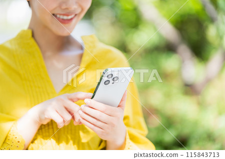 A woman using a smartphone outdoors. 115843713